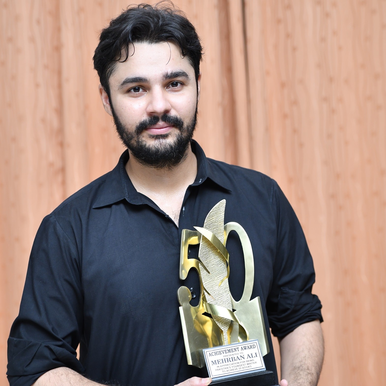 Mehrban Ali holding up achievement award